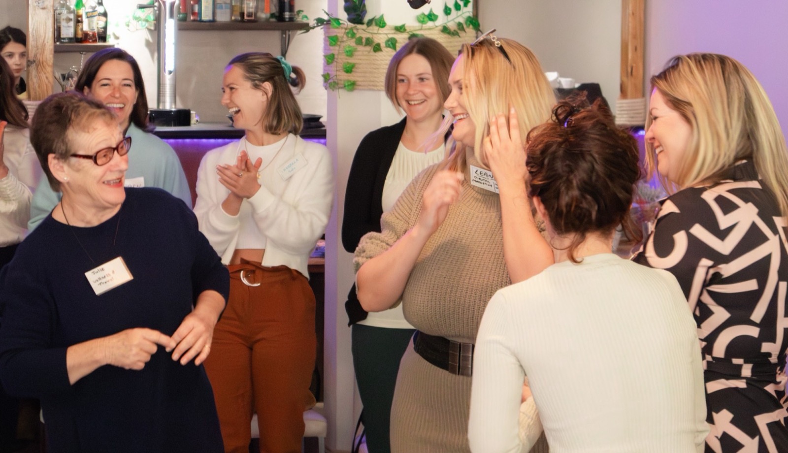 Women laughing and clapping together at a gathering
